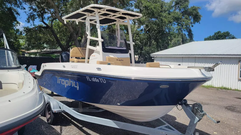 Slide: The Image of 2024 Trophy T20CC boat on trailer, parked outdoors near trees and a building. - 5