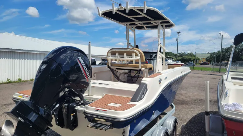 Slide: The Image of 2024 Trophy T20CC boat with Mercury engine, parked outdoors under a clear blue sky. - 7
