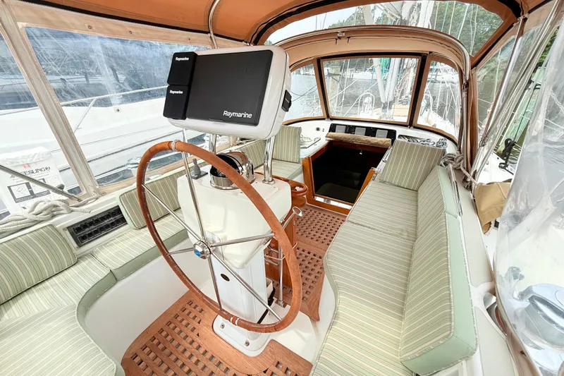 Slide: The Image of 2008 Hylas 46 yacht cockpit with Raymarine navigation, wooden wheel, and striped seating. - 18