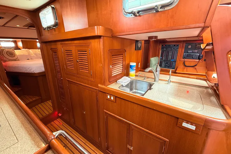 Slide: The Image of Interior of 2008 Hylas 46 yacht featuring a wooden galley with sink and storage. - 26