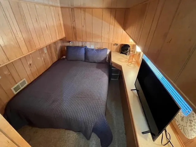 Slide: The Image of Cozy bedroom in 2001 Horizon 16 x 70 houseboat with wood paneling and TV. - 16