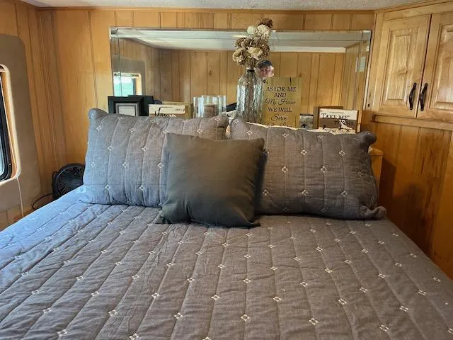 Slide: The Image of Cozy bedroom in 2001 Horizon 16 x 70 houseboat with decorative pillows and wooden paneling. - 19