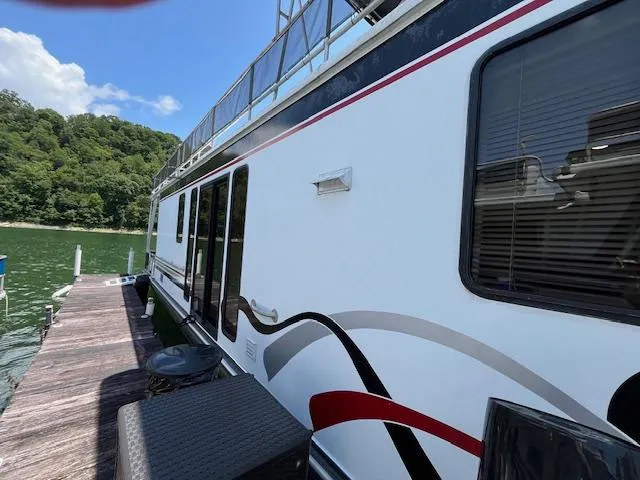 Slide: The Image of 2001 Horizon 16 x 70 houseboat docked on a sunny day, surrounded by lush greenery. - 2