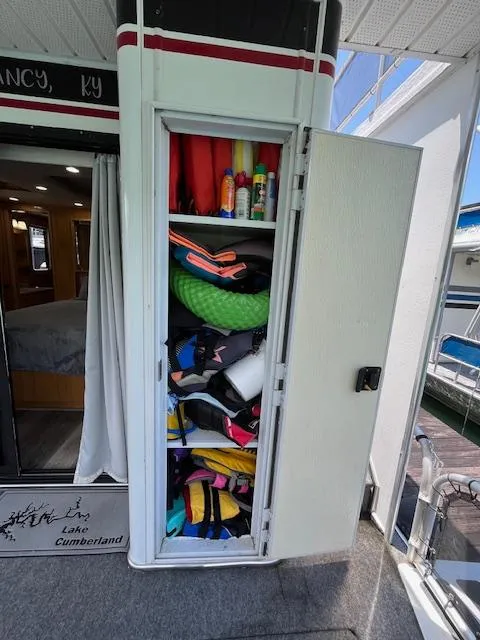 Slide: The Image of Storage cabinet on 2001 Horizon 16 x 70 Houseboat, filled with life jackets and pool noodles. - 34