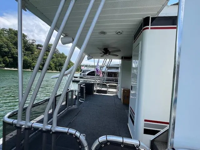 Slide: The Image of 2001 Horizon 16 x 70 Houseboat deck with railing, fan, and scenic water view. - 4