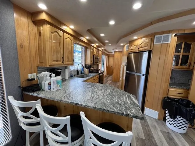 Slide: The Image of Modern kitchen interior of 2001 Horizon 16 x 70 houseboat with granite countertops and wooden cabinetry. - 8