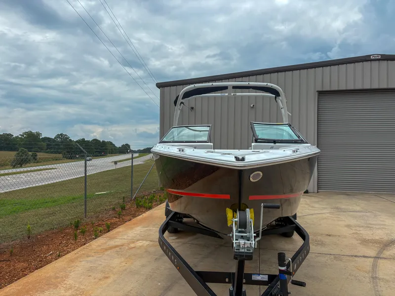 Slide: The Image of 2026 Four Winns H2 Freedom boat on trailer, parked near a metal building under cloudy skies. - 4