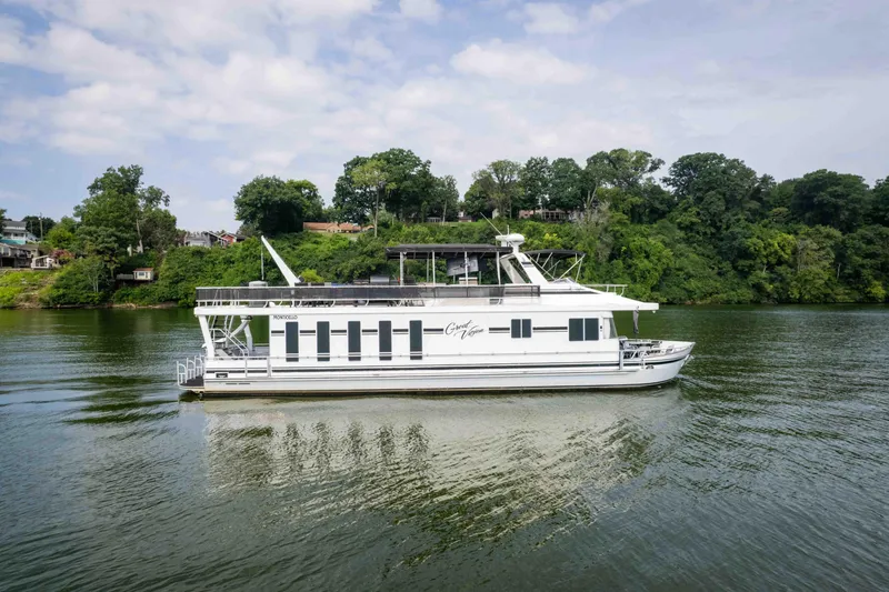 Slide: The Image of 2008 Monticello houseboat cruising on a scenic river with lush green shoreline. - 14