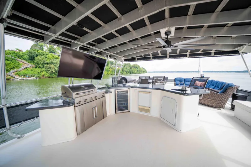 Slide: The Image of Luxurious 2008 Monticello houseboat deck with outdoor kitchen, TV, and seating overlooking serene water. - 17