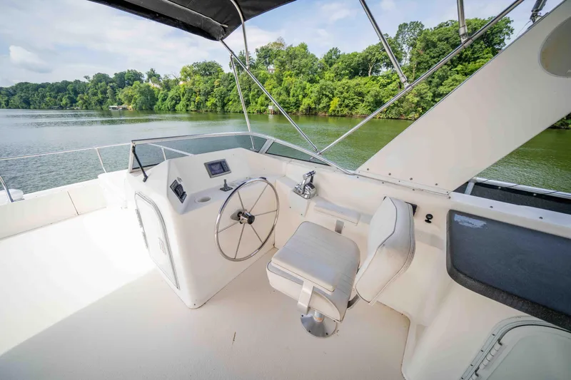 Slide: The Image of 2008 Monticello Houseboat helm with steering wheel, seat, and river view. - 20