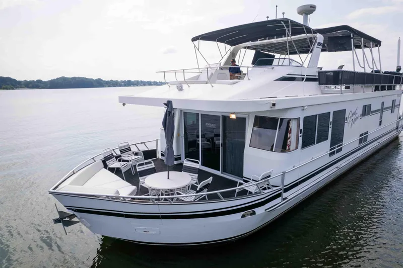 Slide: The Image of 2008 Monticello houseboat on calm water, featuring spacious deck with seating and umbrella. - 3