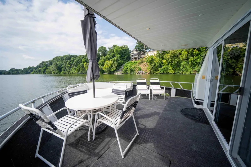 Slide: The Image of 2008 Monticello houseboat deck with chairs, table, and umbrella overlooking a scenic river view. - 31