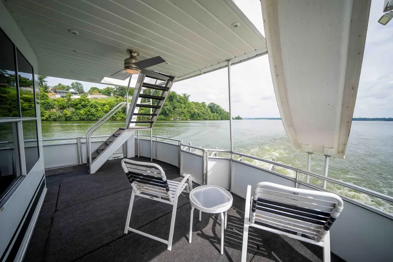 Slide: The Image of 2008 Monticello houseboat deck with chairs, table, and stairs overlooking serene water and lush greenery. - 33