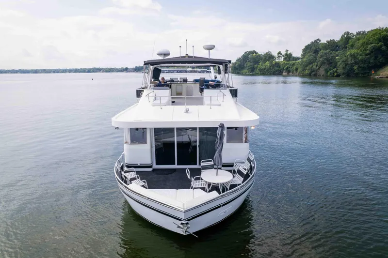 Slide: The Image of 2008 Monticello houseboat on serene lake with lush green shoreline. - 4