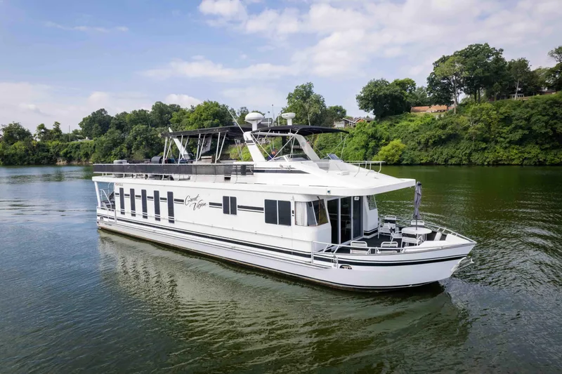 Slide: The Image of 2008 Monticello houseboat cruising on a scenic river with lush green surroundings. - 6