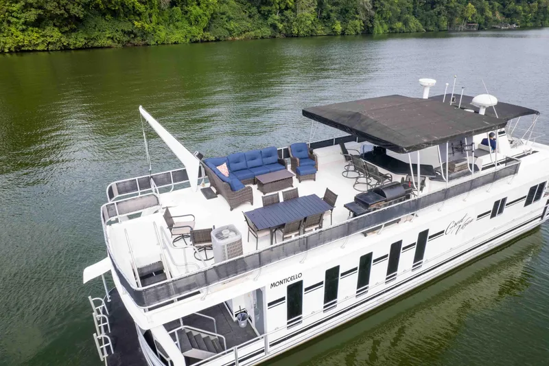 Slide: The Image of Luxurious 2008 Monticello houseboat with spacious deck, seating, and canopy on a serene lake. - 9