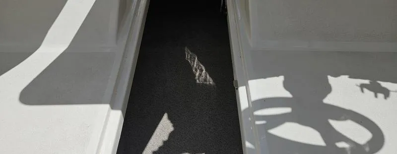 Slide: The Image of Interior view of a 2016 Stingray 225RX boat, featuring shadows and carpeted flooring. - 12