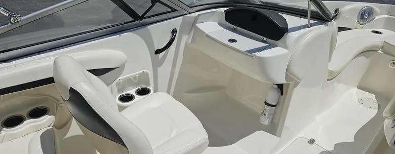 Slide: The Image of 2016 Stingray 225RX boat interior with white seating, cup holders, and dashboard. - 15