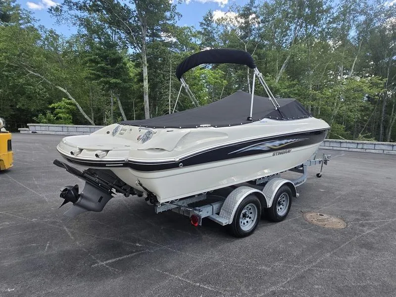 Slide: The Image of 2016 Stingray 225RX boat on trailer, parked outdoors with trees in the background. - 22