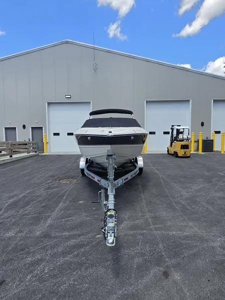 Slide: The Image of 2016 Stingray 225RX boat on trailer, parked outside a large warehouse under a blue sky. - 23