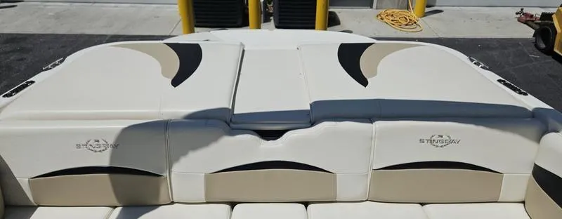 Slide: The Image of 2016 Stingray 225RX boat interior with beige and black seating, docked at a marina. - 4