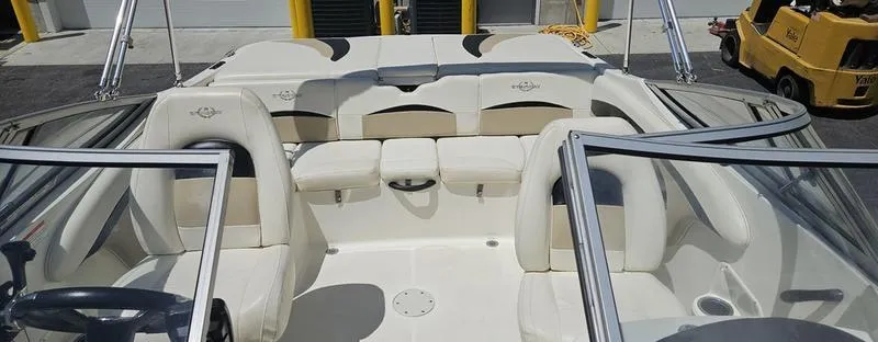 Slide: The Image of 2016 Stingray 225RX boat interior with white seating and steering wheel, docked outdoors. - 8