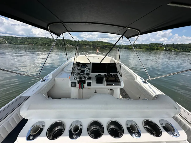 Slide: The Image of 2002 Intrepid 323 Cuddy boat interior with steering wheel, dashboard, and cup holders on a calm lake. - 12