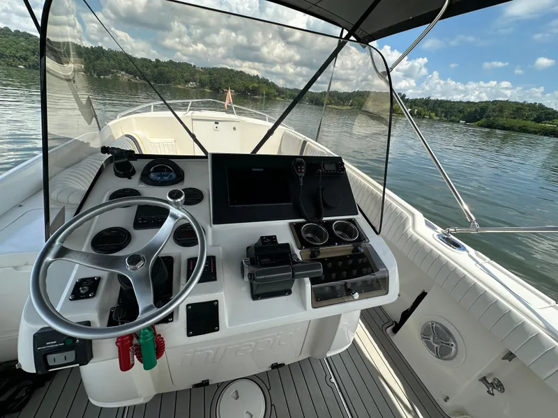 Slide: The Image of 2002 Intrepid 323 Cuddy boat helm with steering wheel and controls on a calm lake. - 13