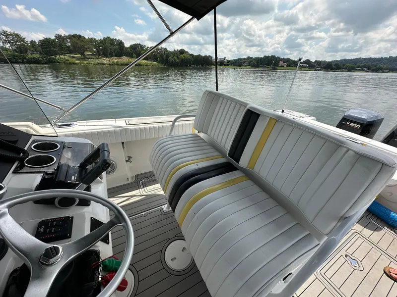 Slide: The Image of 2002 Intrepid 323 Cuddy boat interior with striped seating and steering wheel, on a calm lake. - 14