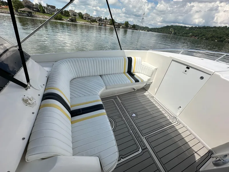 Slide: The Image of 2002 Intrepid 323 Cuddy boat interior with striped seating and scenic lake view. - 16