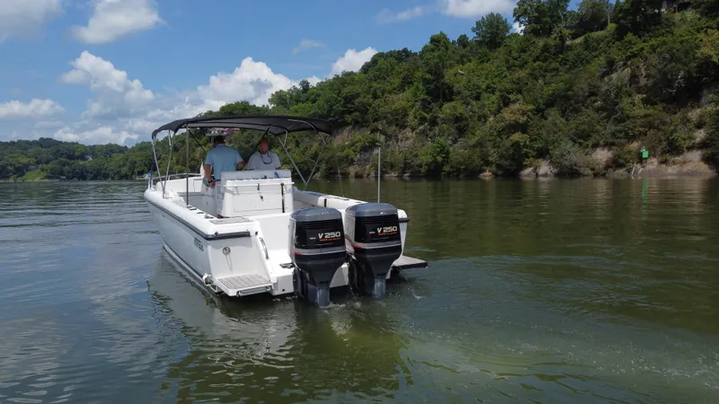 Slide: The Image of 2002 Intrepid 323 Cuddy boat cruising on a scenic lake with lush green shoreline. - 4