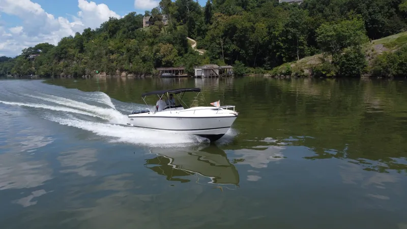 Slide: The Image of 2002 Intrepid 323 Cuddy cruising on a scenic lake with lush green shoreline. - 6