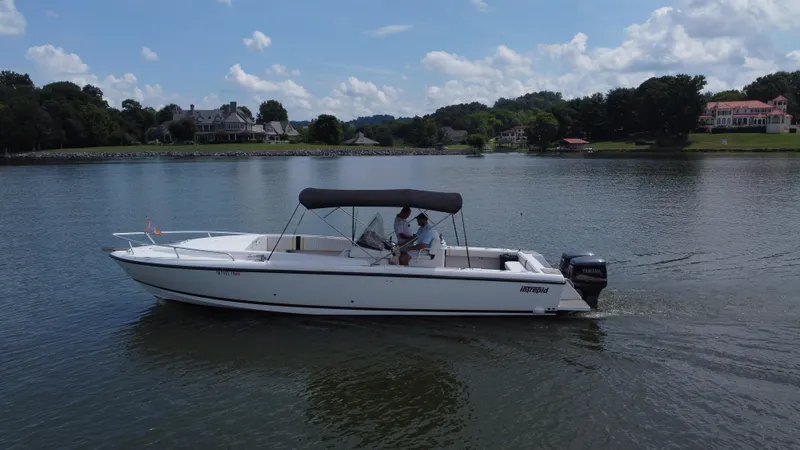 Slide: The Image of 2002 Intrepid 323 Cuddy boat cruising on a calm lake with scenic shoreline. - 8