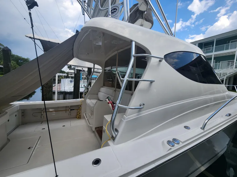 Slide: The Image of 2015 Jupiter 41 SB boat docked, showcasing sleek design and spacious deck under a blue sky. - 6