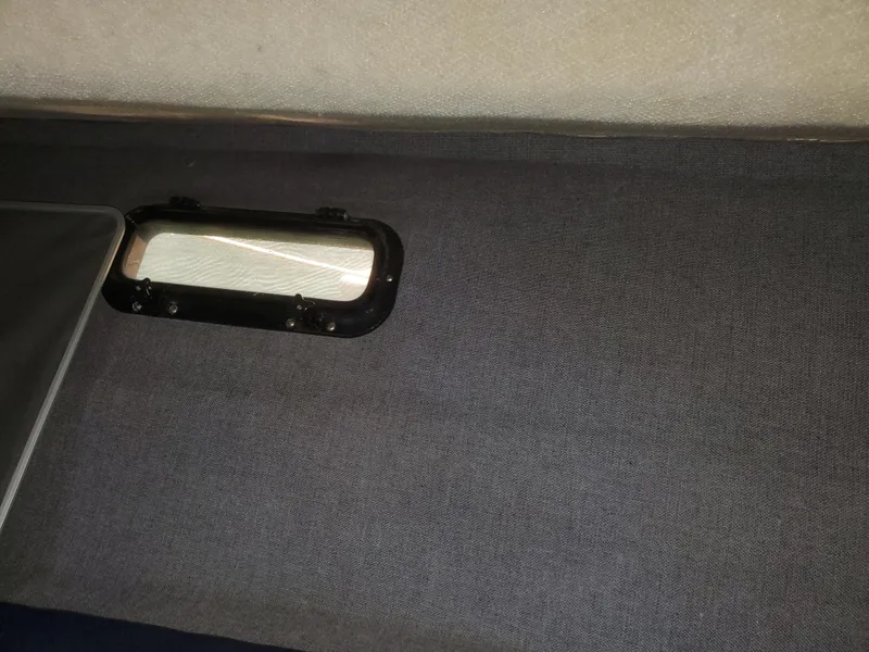 Slide: The Image of Interior view of 1988 Tiara Yachts 2700 Open, featuring a small window and dark upholstery. - 17