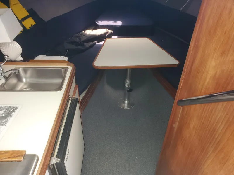 Slide: The Image of 1988 Tiara Yachts 2700 Open cabin interior with table, sink, and compact kitchen area. - 21