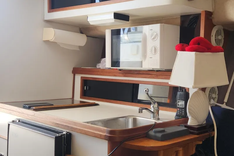 Slide: The Image of 1988 Tiara Yachts 2700 Open cabin with sink, microwave, and lamp. - 28