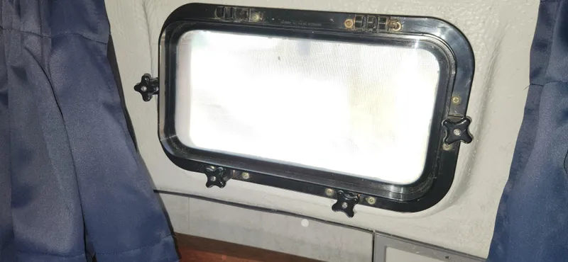 Slide: The Image of Porthole window inside a 1988 Tiara Yachts 2700 Open, with blue curtains. - 34