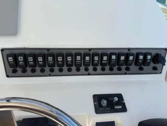 Slide: The Image of Control panel of a 2015 Wellcraft 290 Coastal boat with multiple switches and spotlight controls. - 11