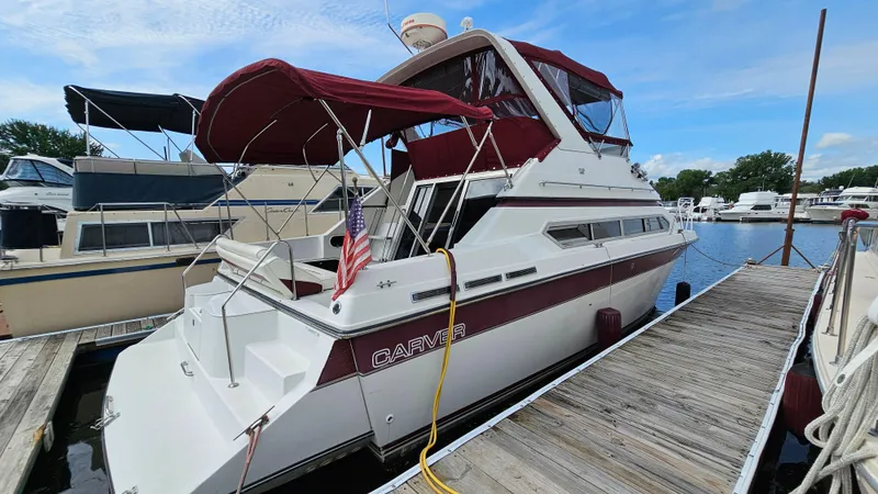 The Image of 1989 Carver 38 Santego yacht docked, featuring maroon canopy and American flag. - 1