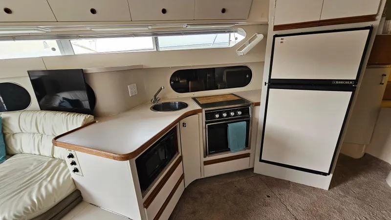 Slide: The Image of 1989 Carver 38 Santego yacht interior with kitchen, featuring stove, sink, and refrigerator. - 19