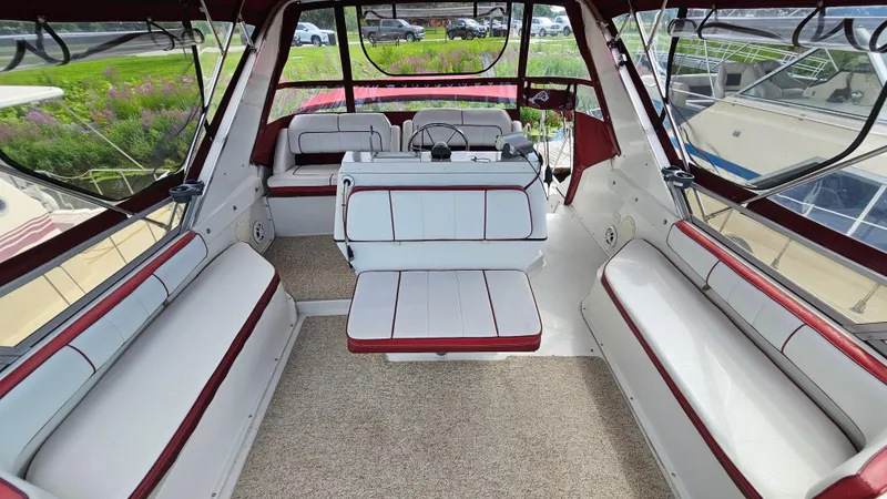 Slide: The Image of 1989 Carver 38 Santego boat interior with white and red seating, spacious layout, and large windows. - 7