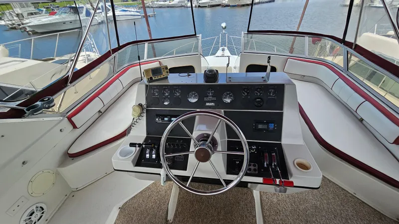 Slide: The Image of 1989 Carver 38 Santego yacht helm with steering wheel, controls, and marina view. - 9