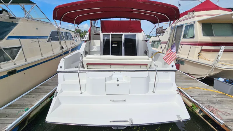 Slide: The Image of 1989 Carver 38 Santego yacht with red canopy, docked between boats, American flag displayed. - 4