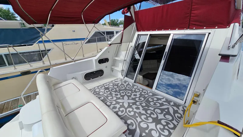 Slide: The Image of 1989 Carver 38 Santego yacht with red canopy, patterned deck rug, and sliding glass doors. - 6