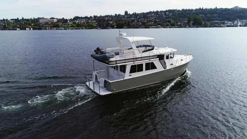 Slide: The Image of 2025 Helmsman Trawlers 43E Pilothouse cruising on a scenic lake. - 0