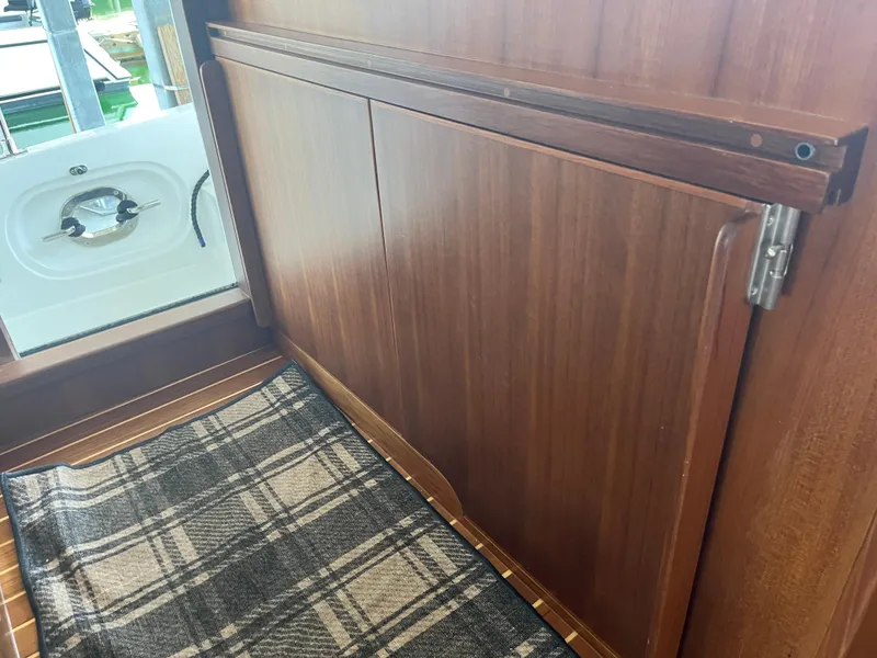 Slide: The Image of Interior of 2025 Helmsman Trawlers 43E Pilothouse with wood paneling and plaid rug. - 23