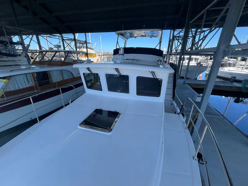 Slide: The Image of 2025 Helmsman Trawlers 43E Pilothouse docked under a marina roof. - 26