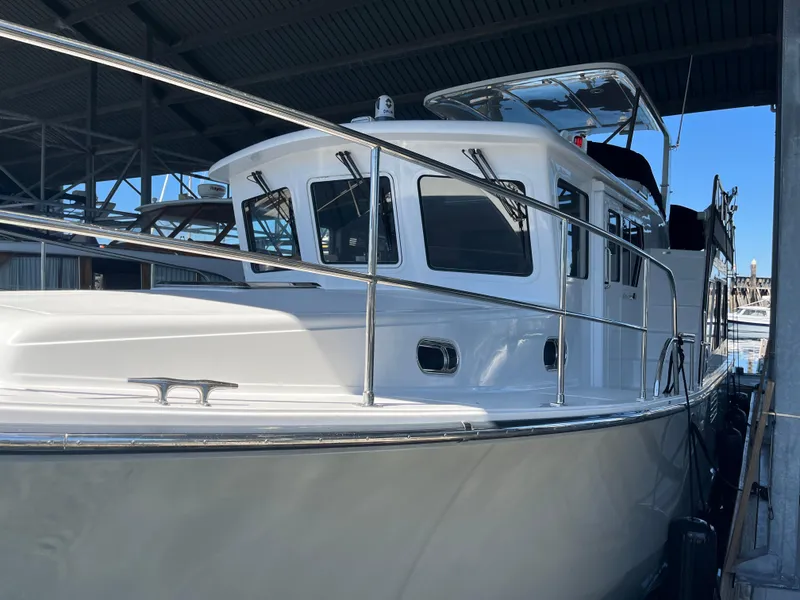 Slide: The Image of 2025 Helmsman Trawlers 43E Pilothouse boat docked under a covered marina. - 27