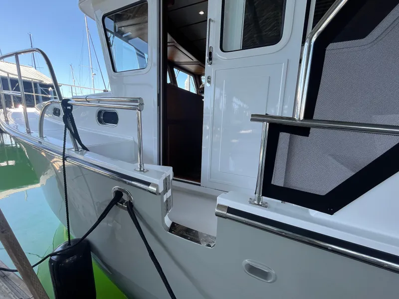 Slide: The Image of 2025 Helmsman Trawlers 43E Pilothouse yacht, side view with open door and railing. - 28